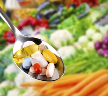 spoon with pills, dietary supplements on vegetables background
